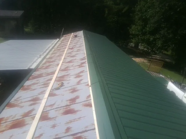 Old rusted panels beside newly installed green metal roofing — Wind Damage Roof Repair by Roofing Brothers in Cheyney