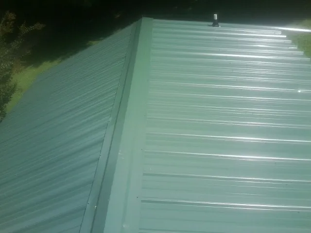 New green metal panels meeting at the ridge of a roof — Flat Roof Repair work by our crew in Cheyney