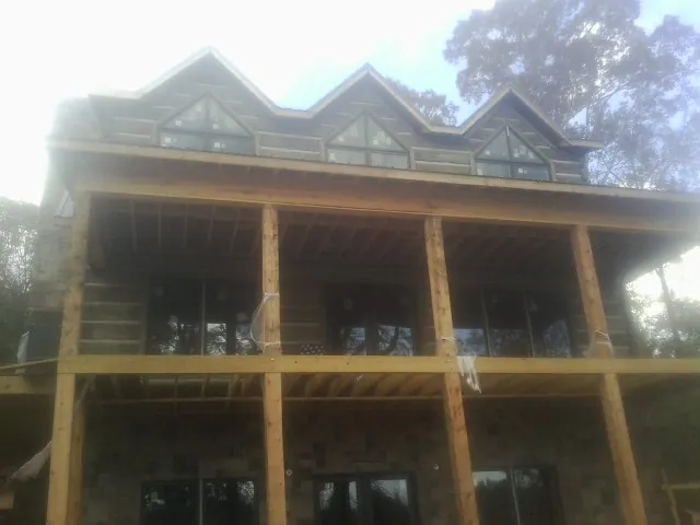 Dormers and porch framing on a large log home under construction — Roof Coating work by our crew in Cheyney