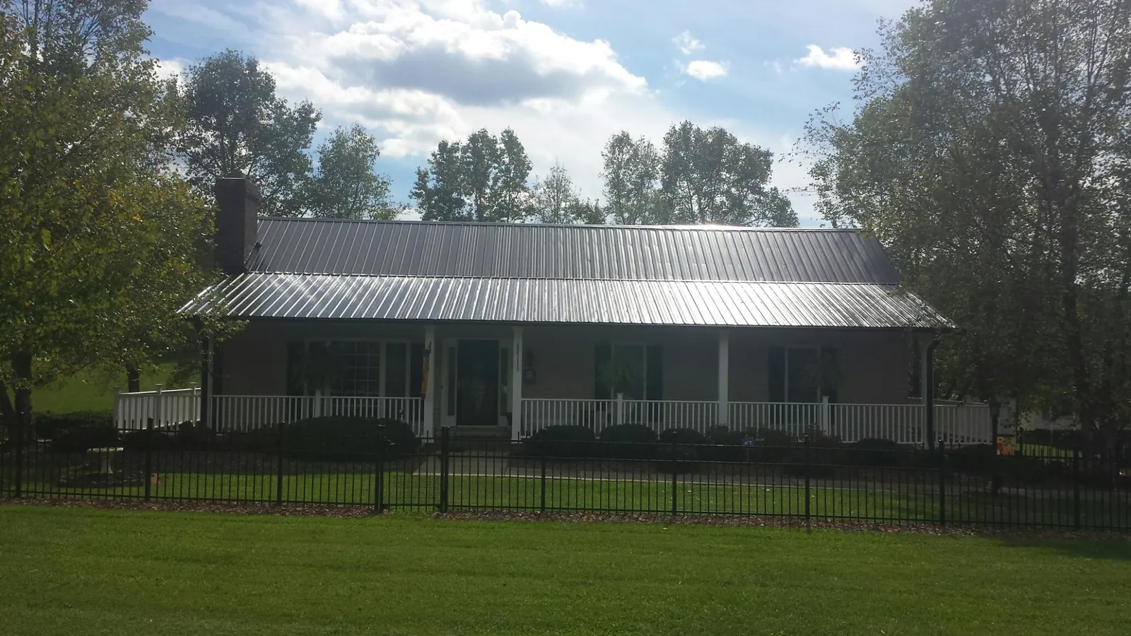 Gray metal roof on a brick ranch with a full width front porch — Gutter Guard Installation work by our crew in Cheyney