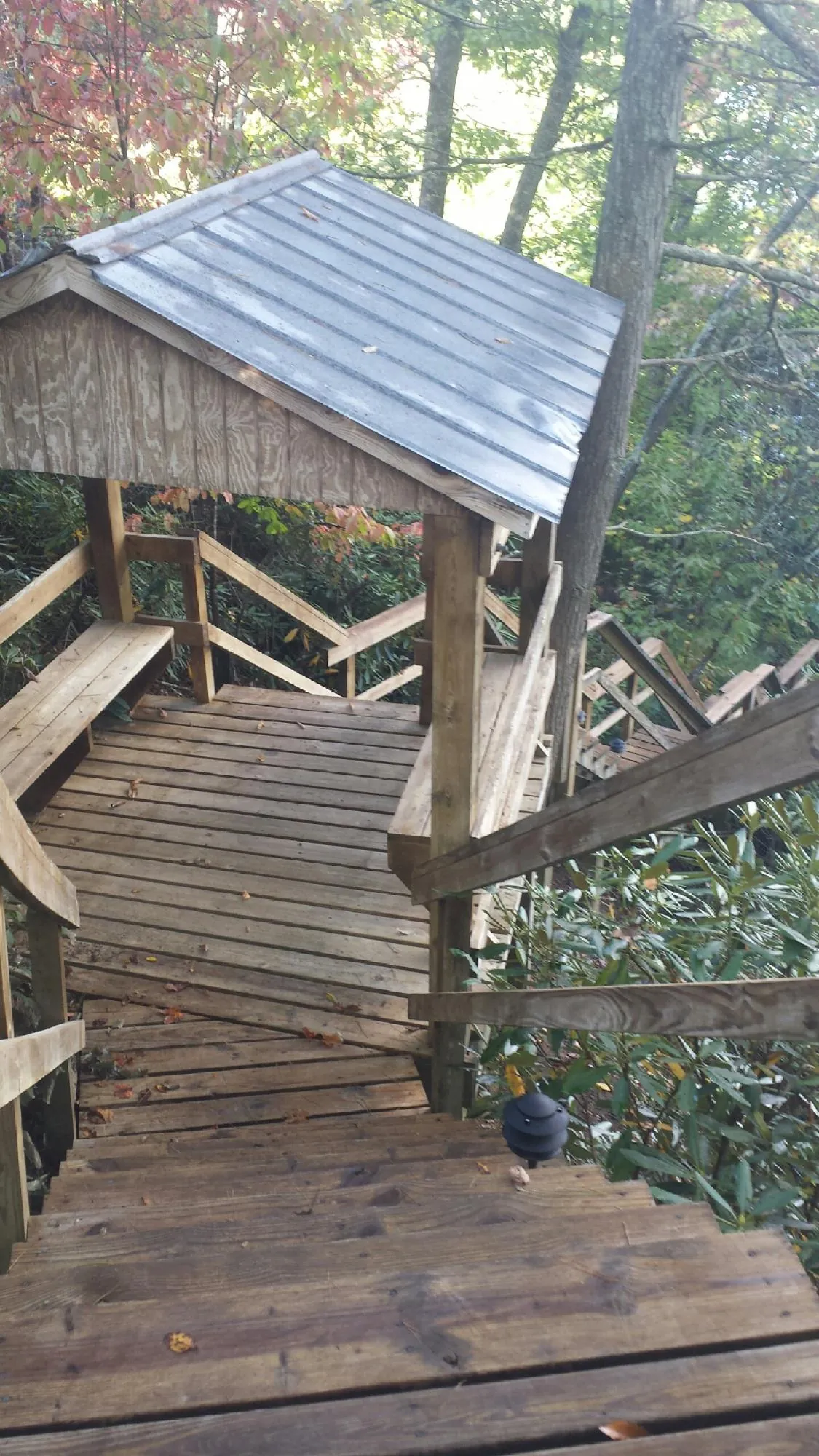 Metal roofed shelter over wooden steps on a wooded walkway — Skylight Repair & Installation work by our crew in Cheyney