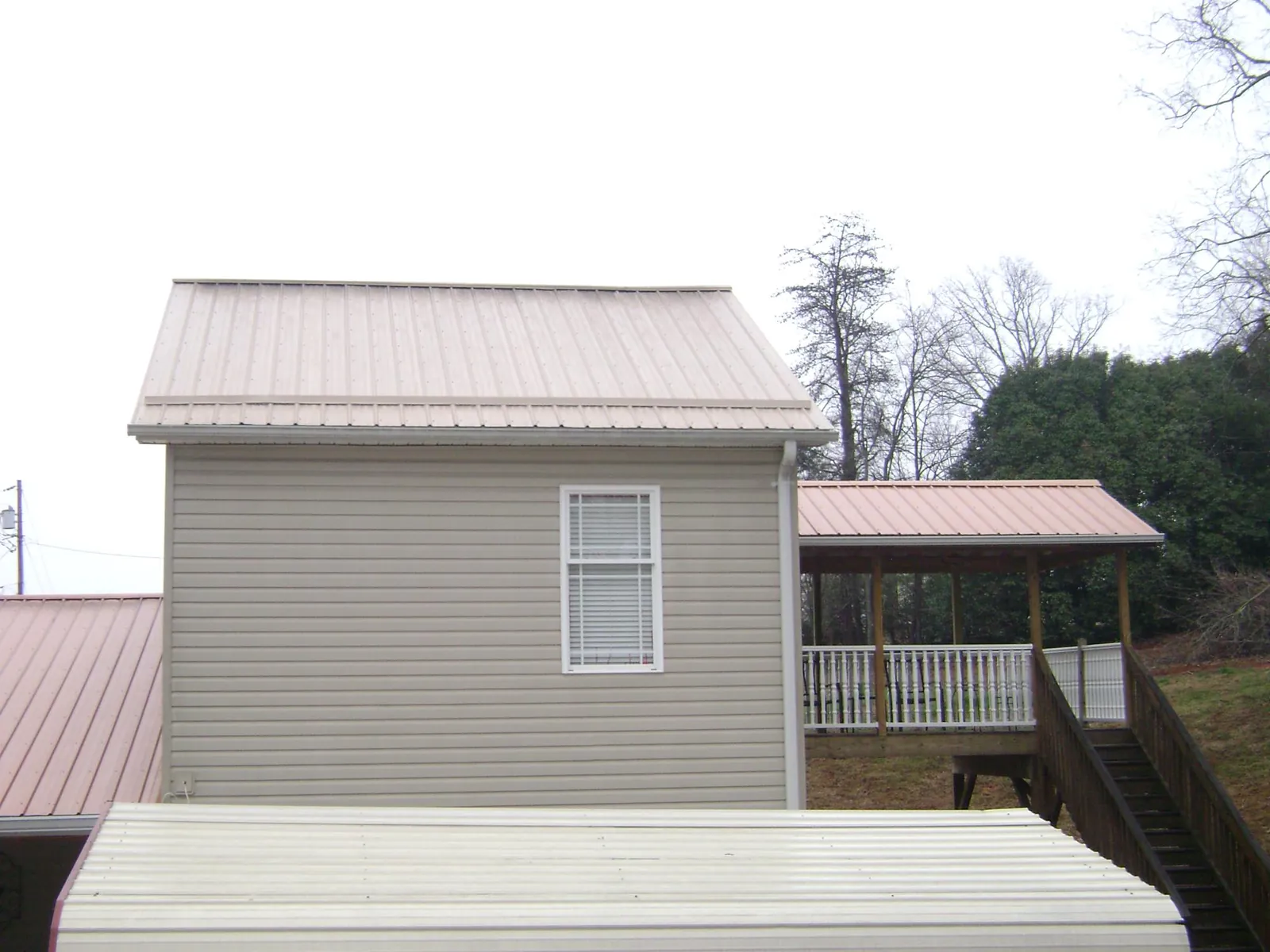 Tan metal roofs on a two story addition and attached porch, from a Roof Replacement job in Cheyney
