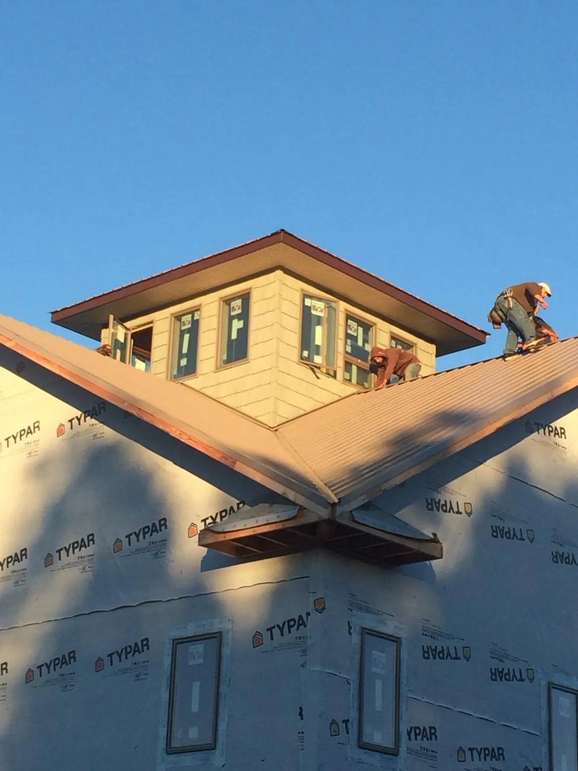 Roofers working around a rooftop cupola on a new metal roof at sunset — Roof Waterproofing in Cheyney by Roofing Brothers